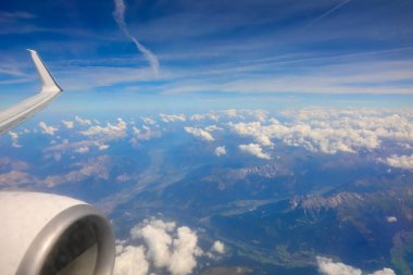 breathtaking aerial view of white clouds and mountains with a piece of airplane wing and turbojet engine in flight clipart