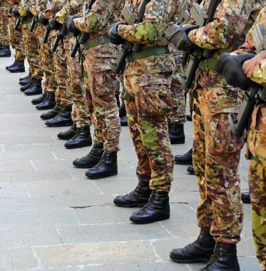 Black combat boots of army soldiers in camouflage uniforms standing at attention in formation clipart