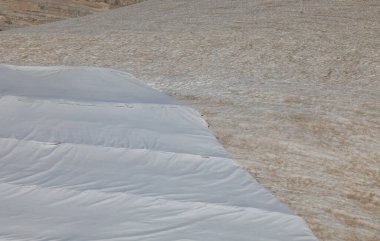 Avrupa Alpleri 'ndeki Marmolada dağ buzulu 3.000 metrenin üzerinde, örülmemiş koruyucu kumaş örtüsü ve iklim değişikliği nedeniyle rüzgarın taşıdığı kırmızı kumla birlikte.