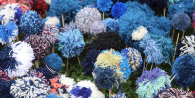 Çimenlerin üzerine dizilmiş iplik ponponları ile yaratılmış sahte çiçeklerden yapılmış çiçek tarhı