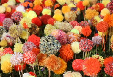 Renkli yün ipliklerden yapılmış gerçek çiçeklere benzeyen ponponların arka planı