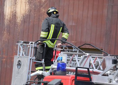 Korkusuz itfaiyeci acil bir durum sırasında mavi bir sirenle itfaiye merdiveninde güvenle yürüyor.