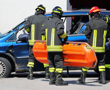 Otoyol kazasından sonra üniformalı itfaiyeciler turuncu sedyeyle yaralılara yardım ediyor.