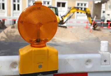 Koruyucu bariyere takılı yanıp sönen turuncu lamba, sürücüleri ileride etkin bir inşaat bölgesi olduğu konusunda uyarıyor.