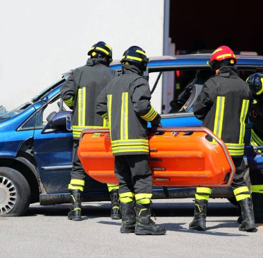 Otoyoldaki kazadan sonra üniformalı itfaiyeciler turuncu sedyeyle yaralılara yardım ediyor.