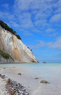 Danimarka 'daki Mons Klint' in yükselen beyaz tebeşir kayalıklarının kristal berrak Baltık Denizi 'ne çarpıcı bir şekilde düşüşü.