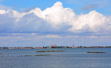 Ufukta Valli Di Comacchio kasabası, ünlü bir balıkçı kasabası ve deniz ve beyaz bulutlar olan lagün.