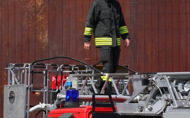 Korkusuz itfaiyeci acil bir durum sırasında mavi bir sirenle itfaiye merdiveninde güvenle yürüyor.