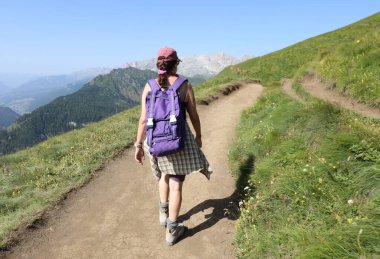 Genç yalnız kadın yürüyüşçüleri yazın İtalyan Alplerinde omuzlarında bir sırt çantasıyla Dolomitler üzerinde yürürler.