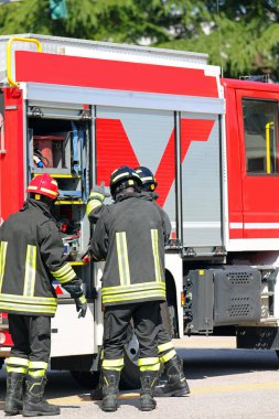 three firefighters take specialized rescue equipment from red fire engine clipart