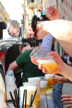 Açık hava köy festivali sırasında bardağa çok taze bira dolduran barmenin eli.