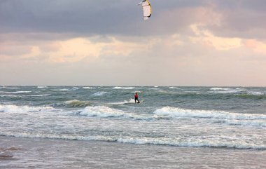Çok cesur sporcu Kitesurfing adlı bir ekstrem sporla uğraşıyor dalgalı bir okyanusun üzerinde rüzgarlı bir günde