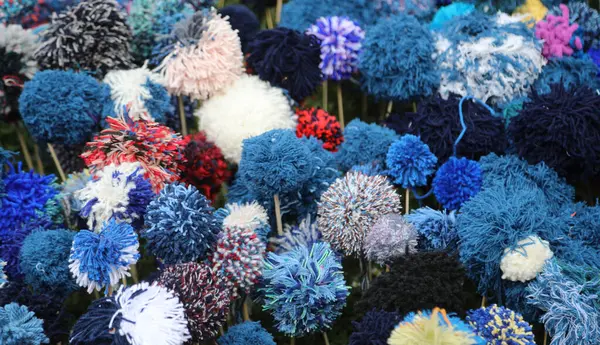 İnanılmaz renkli bir arka plan oluşturan yün iplik ponponlardan yapılmış bir sürü çiçek.