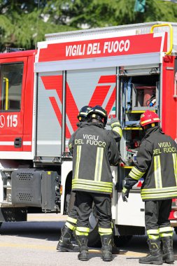 Vicenza, VI, İtalya - 23 Mayıs 2024: İtfaiyeciler acil ve kırmızı bir kamyon sırasında üzerinde İtalyanca yazı olan üniformalar giyiyorlar.