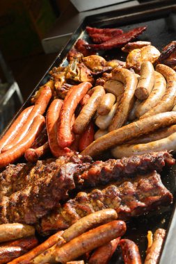 mixed grill with pork ribs and sausages cooked on a hot griddle during a village festival clipart