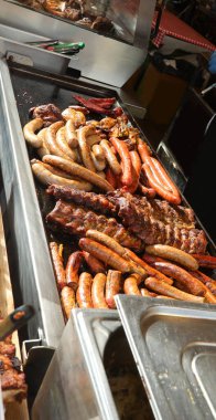 mixed grill with pork ribs and sausages cooked on a hot griddle during a village festival at the open-air restaurant clipart