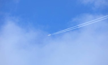 Turistik bölgelere uçuş sırasında ticari bir uçağın bıraktığı mavi gökyüzündeki beyaz iz.