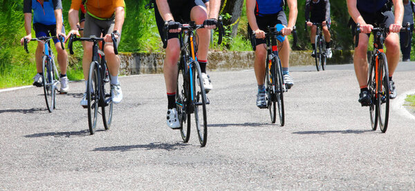 Многие велосипедисты, которые крутят педали на дороге во время велогонки на гоночных велосипедах