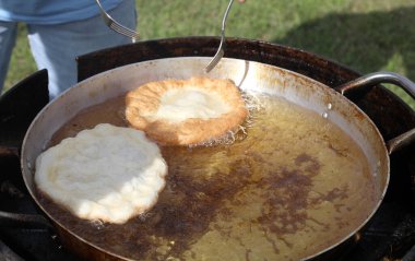 two large fritters that are cooked in boiling oil during the village festival clipart