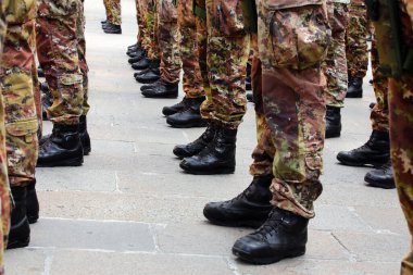 Black combat boots of army soldiers in camouflage uniforms standing at attention in formation clipart