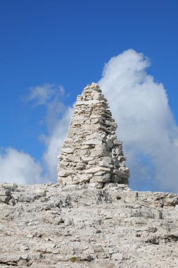 very big pile of stones known as a cairn sits high in the mountains symbolizing either a prayer or a wayfinding marker in the European Alps clipart