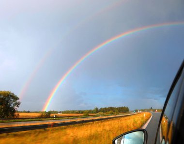 Fırtınadan sonra ovalarda bir yolculuk sırasında bir arabadan görülen güzel çift gökkuşağı.
