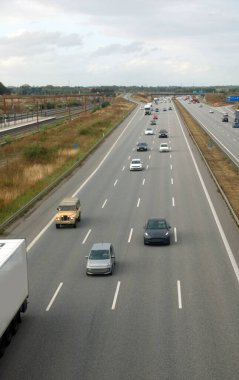 very wide four-lane highway with cars and more vehicles speeding along the straight road seen from above clipart