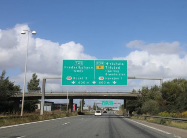 Danimarka 'da otoyoldaki yol tabelası birden fazla yerin yönünü gösteriyor ve açık sürüş talimatları veriyor