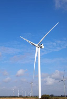 Rüzgâr enerjisiyle dönen uzun rüzgar türbini elektrik üretmek için bir alana yerleştirilmiş.