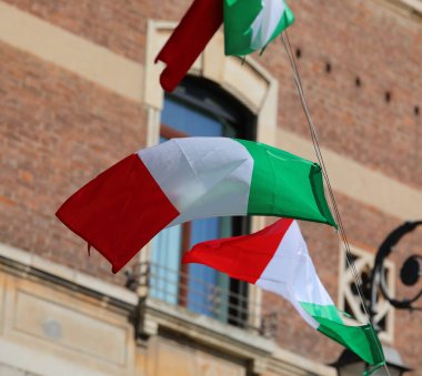 Rüzgarda dalgalanan yeşil kırmızı üç renkli bayraklar ve arka plandaki tuğlalardan yapılmış tarihi bina