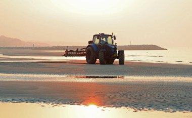 Tatilciler gelmeden önce deniz kenarındaki sahili temizlemek için traktör kullanıldı.