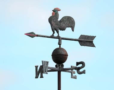 Antique vintage metal weathervane featuring a rooster with a large tail on top along with an arrow and cardinal direction letters clipart