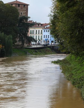 Çamurlu nehir FIUME BACCHIGLIONE şiddetli yağmur ve Kuzey İtalya Vicenza 'daki eski Ortaçağ Kulesi sırasında taştı