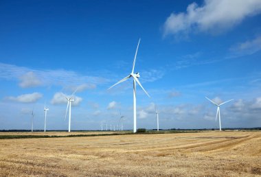Düz bir tarla boyunca rüzgar enerjisini kullanarak elektrik üreten çok sayıda türbini olan uçsuz bucaksız bir rüzgar çiftliği.