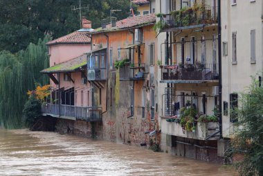 house sits close to a river that is flooding due to heavy rain caused by climate change clipart