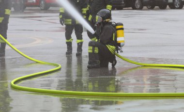 İtfaiyeciler yangın söndürme operasyonu sırasında oksijen tüpü takıp köpük püskürterek hortumla söndürüyorlar.