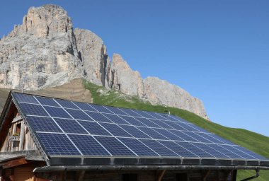 Sürdürülebilir enerji üretimi için güneş ışığından yararlanarak elektrik üreten birçok güneş paneline sahip bir dağ evi.