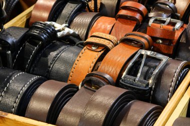 Yetenekli deri ustası deri eşya mağazasında satılık el yapımı metal tokalarla bir dizi deri kemer yapmış.