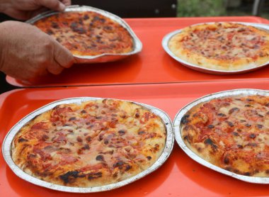 Pizzacının eli az önce fırından domates soslu ve mozzarella peynirli margherita pizzası çıkardı.