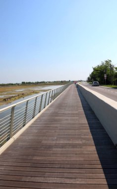 Çamurlu göl ile araba yolu arasında uzun ve modern bir bisiklet yolu var.