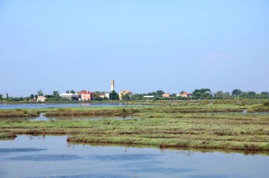 burano island near venice in northern italy with the leaning bell tower and venetian lagoon with low tide clipart