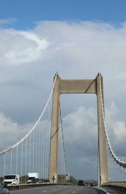 Asma köprünün güçlü güçlendirilmiş beton altyapısı ve üzerinden arabalar geçiyor.