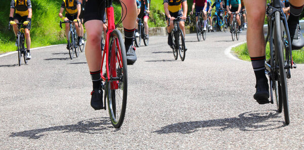 колеса гоночных велосипедов как велосипедисты поднимаются на крутой горный перевал во время соревновательной дорожной гонки