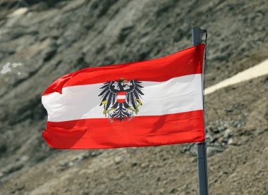 Beyaz ve kırmızı Avusturya bayrağı taçlandırılmış kartal sembolü ve kayalık arkaplan