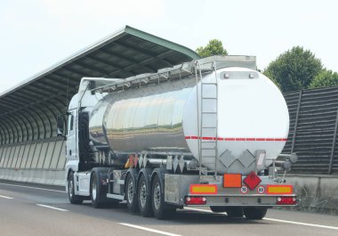 fuel tanker truck speeding toward refueling stations and highway noise barriers on the road clipart