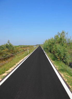 Yeni asfaltlanmış siyah yol. Hiçliğin ortasında, ovalarda, yazın yanında kimse olmadan.
