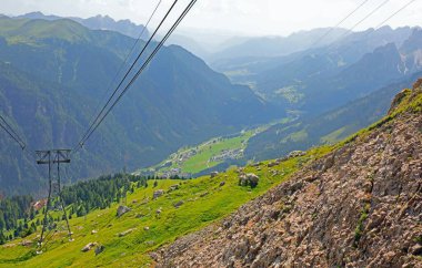 Steel cables and support towers of a cable car system and the valley in northern Italy during summer