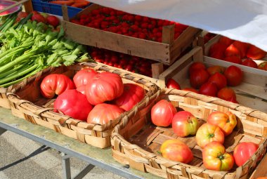 farmers market with many fresh red tomatoes for sale in crates and other vegetables clipart