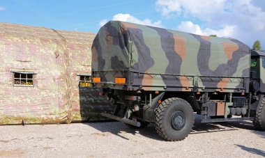 Savaş hattı yakınında kamuflaj çadırları olan savaş malzemelerini kampa taşımak için askeri bir kamyon.