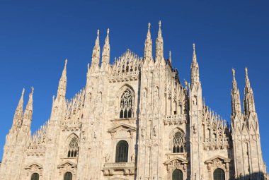 bottom view of Facade of Cathedral of Milan also called DUOMO DI MILANO in italian language in gothic style with blue sky clipart